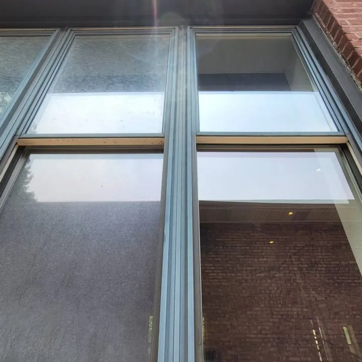 Commercial window cleaning before and after — hazy storefront pane on left, clear glass with visible reflections on right