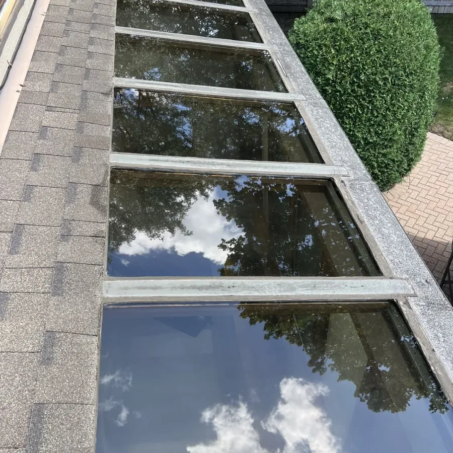 The same sunroom glass panels after cleaning, clear and reflecting the sky