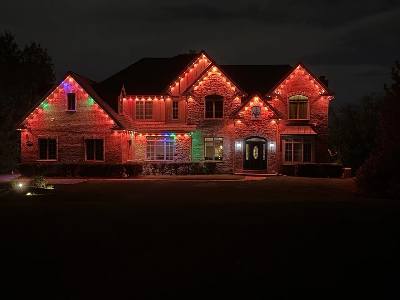 Sparkle Service worker on a ladder mounting a permanent LED light track along a residential roofline