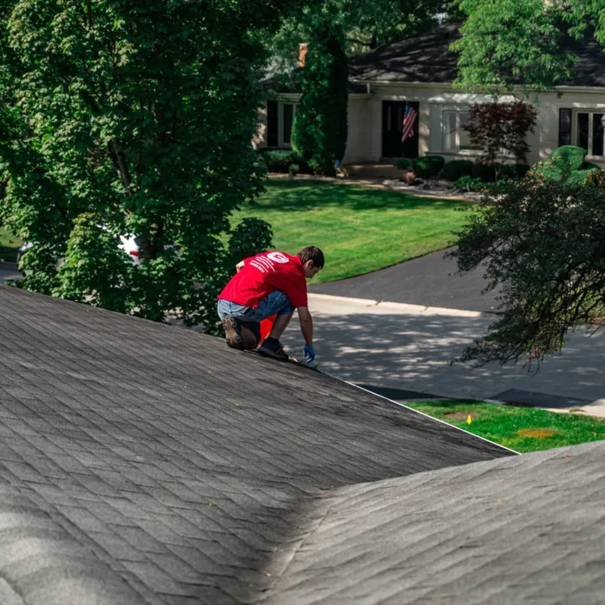 Roof soft washing — worker applying low-pressure foam solution to asphalt shingles