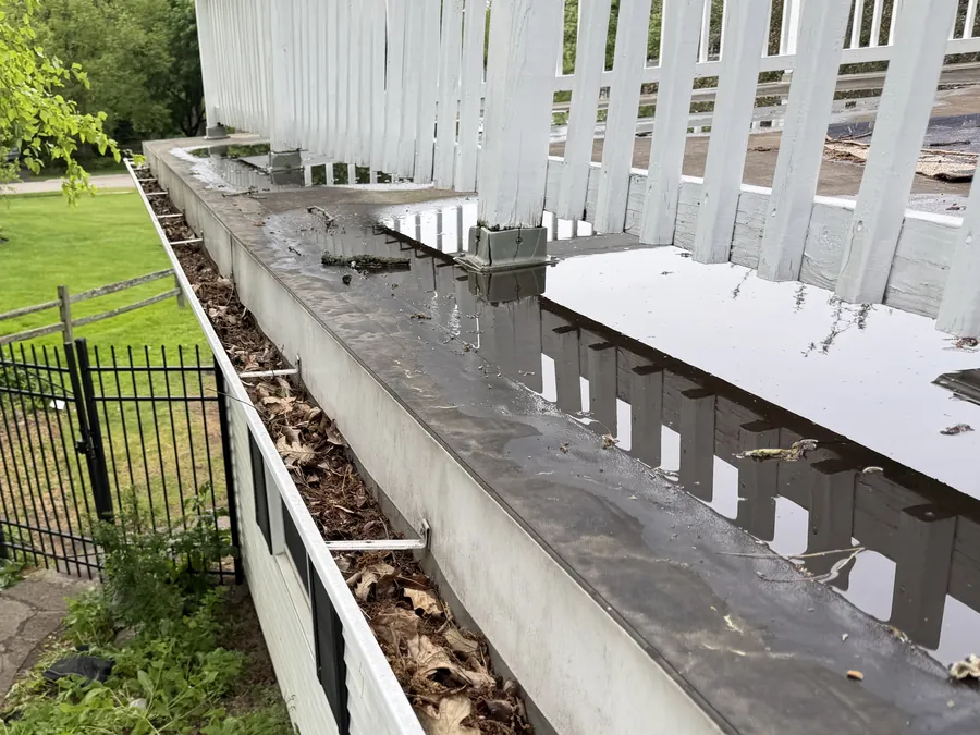 A deck gutter packed with leaves before cleaning