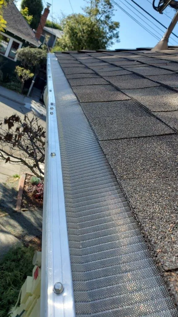 Aluminum micro-mesh gutter guard installed on a K-style gutter along a shingle roof