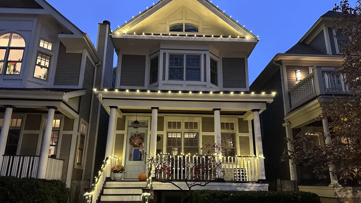 Warm white C9 roofline lights with a lit porch railing and front steps at dusk