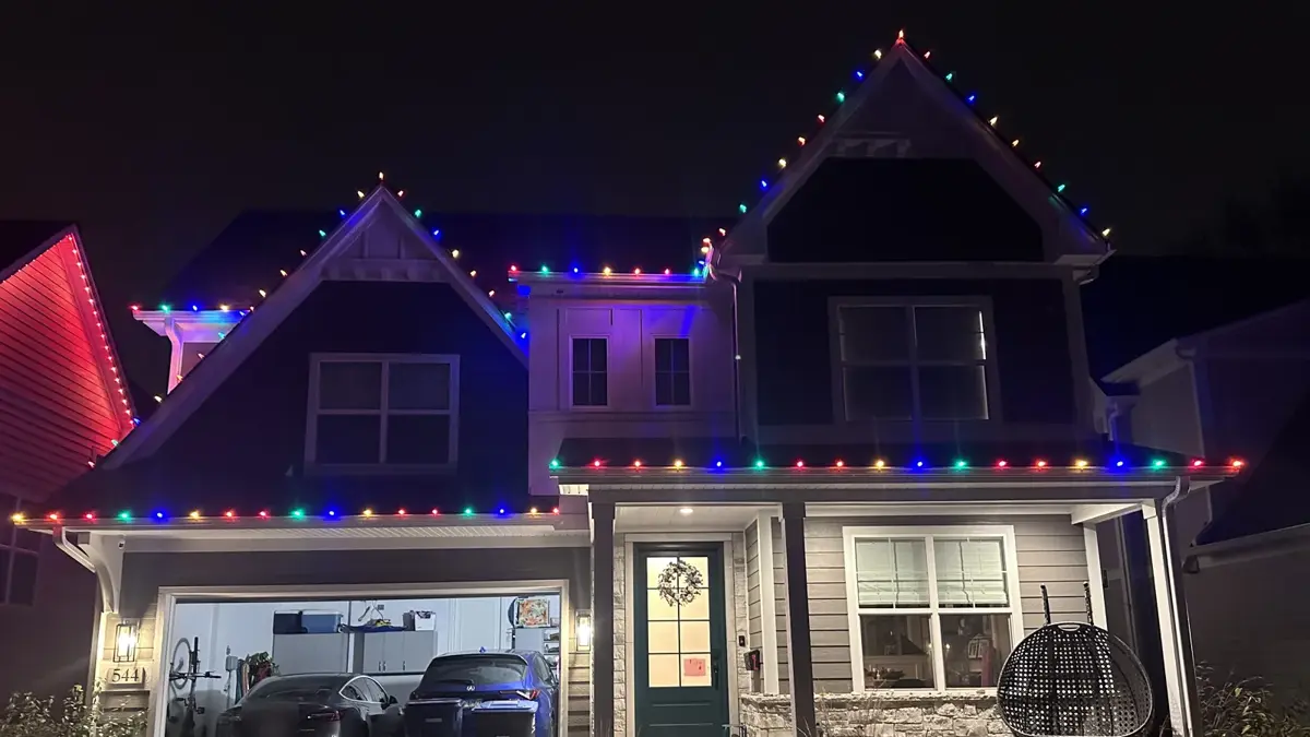 Multicolor C9 holiday lights outlining the gables and rooflines of a two-story home at night