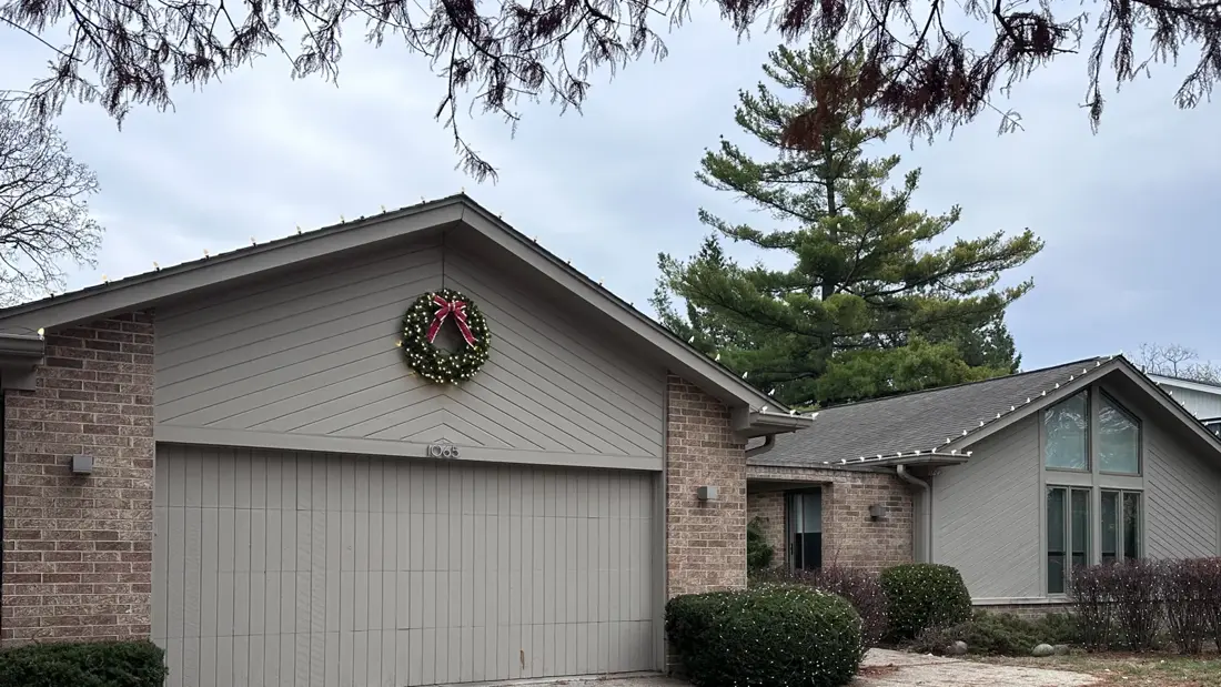 Single-story Glencoe home with warm white C9 roofline lights, a lit wreath on the garage gable, and mini lights on the foundation shrubs