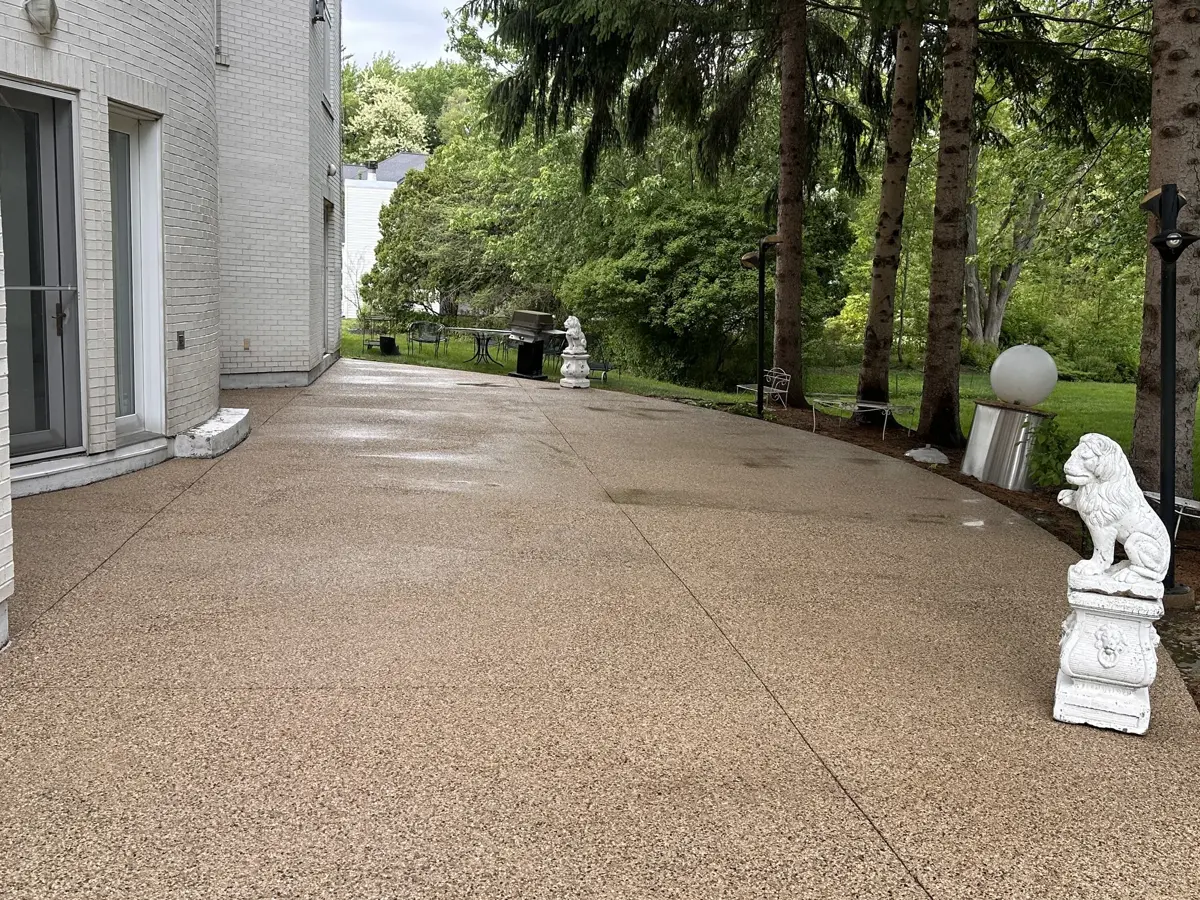 Washed exposed-aggregate driveway running alongside a white brick North Shore home