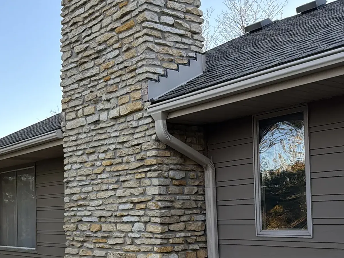 The same stone chimney and siding after a soft wash, the streaking gone