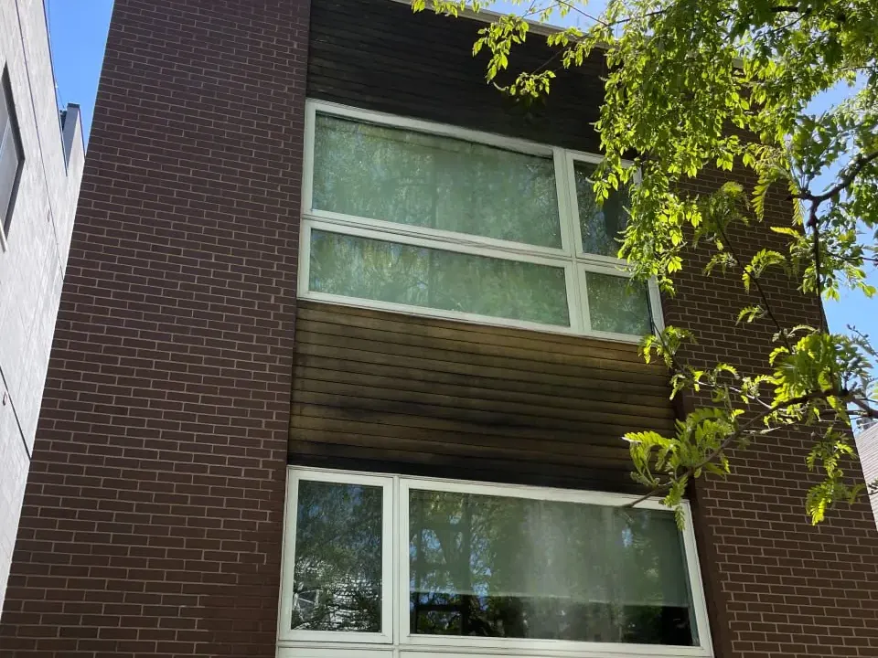 Horizontal wood siding on a Chicago three-flat before washing, the boards weathered grey and streaked